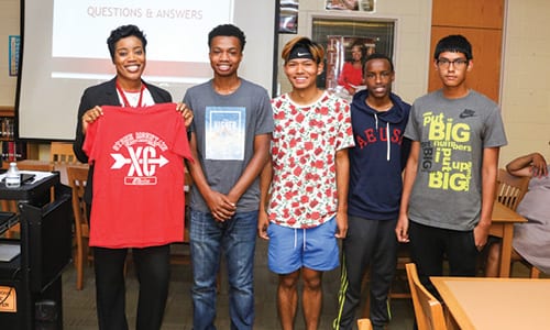 L-R: Stone Mountain principal Dr. Wislene John receives a t-shirt and is made an honorary member of the cross country team by members Marcus Wilson, Kun Aung, Mohamed Nuur and Oliver Ochoa.