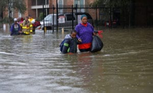 Residents wade through floodwaters from heavy rains in the Chateau Wein Apartments in Baton Rouge, La., Friday, Aug. 12, 2016. Heavy downpours pounded parts of the central U.S. Gulf Coast on Friday, forcing the rescue of dozens of people stranded in homes by waist-high water and leaving one man dead who became trapped by floodwaters. (AP Photo/Gerald Herbert)