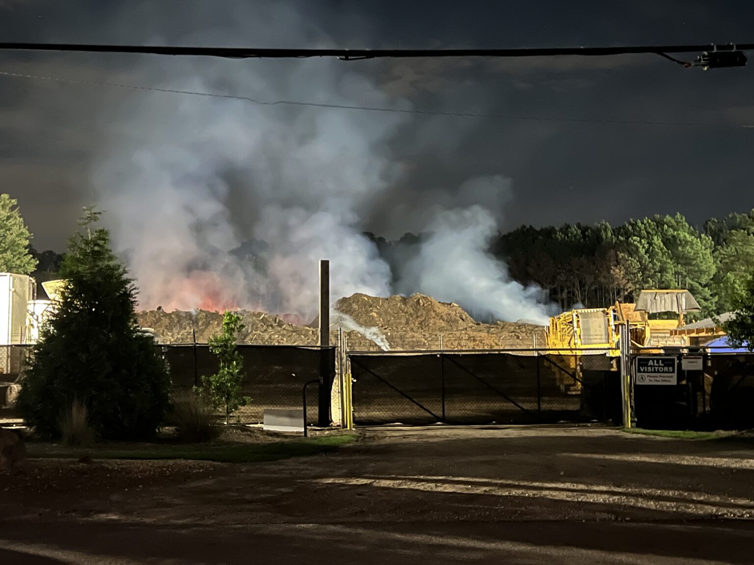 DeKalb County Fire Rescue monitoring large burning mulch and tree pile in unincorporated Lithonia